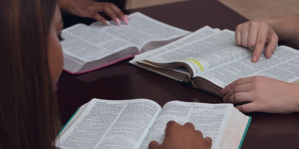 Several open Bibles spread across a table, reflecting Spurgeon's deep commitment to the study and faithful exposition of Scripture.