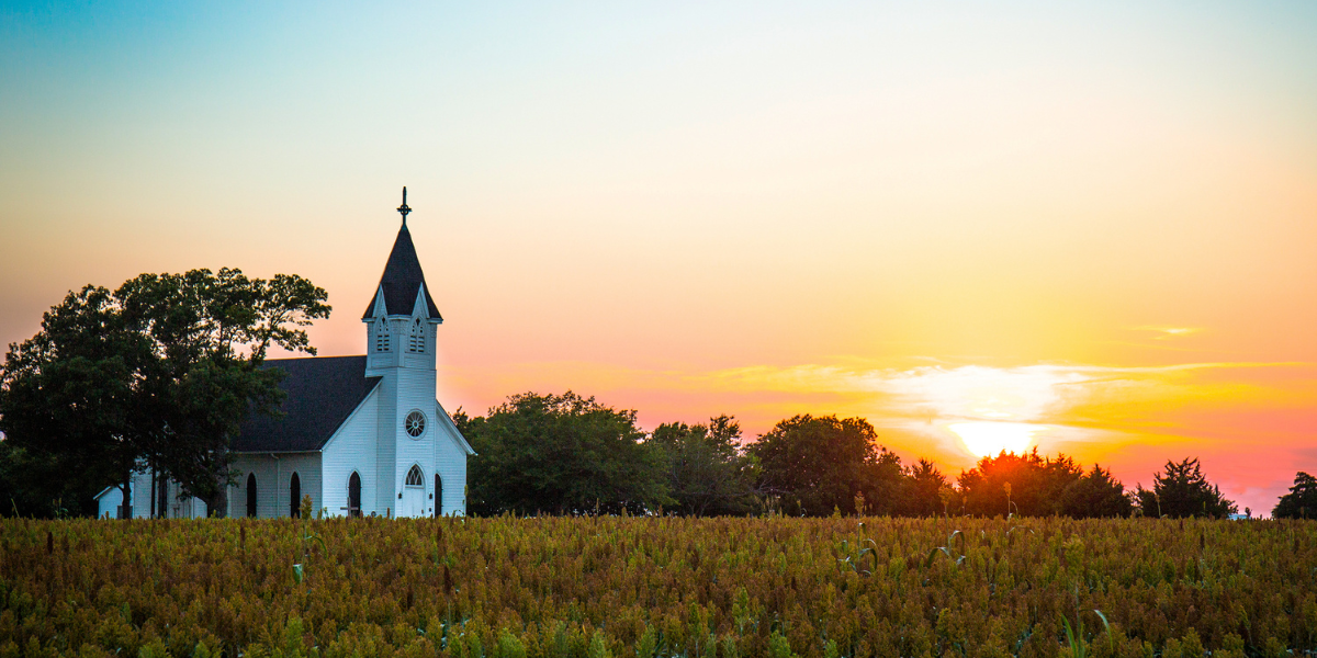 A white country church at sunset surrounded by golden fields, evoking the Jesus-centered freedom and purpose explored in Free of Me by Sharon Hodde Miller