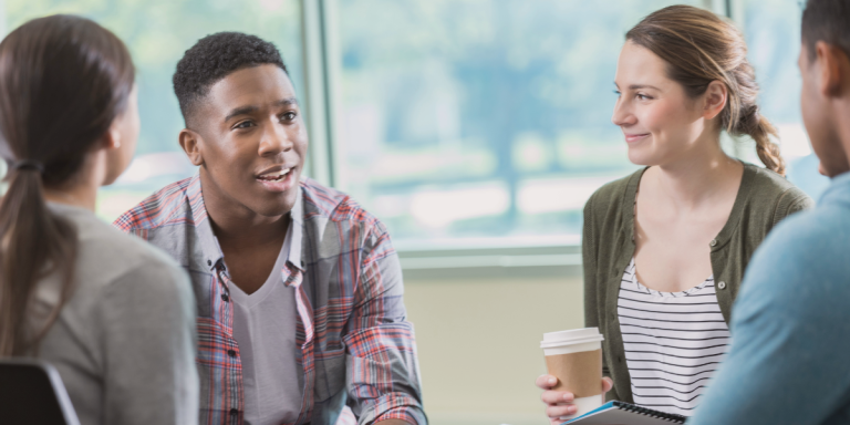Diverse group of young adults engaged in conversation at a church or ministry meeting, representing the multigenerational and multiethnic vision of a future-focused church.